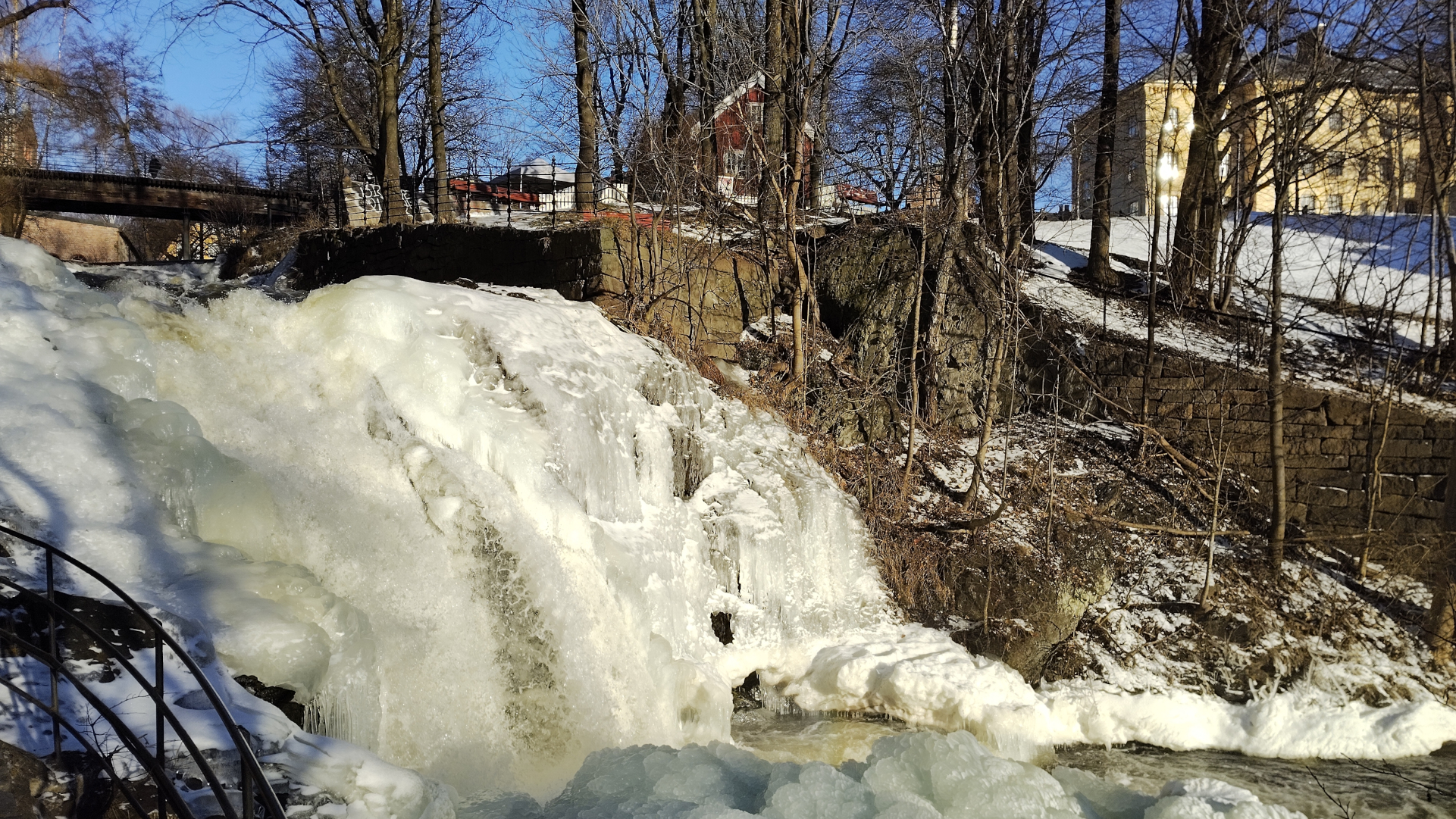 Frozen waterfall, with trees and building around it