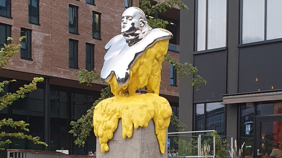 A statue for of a man where the lower part of it appears to be melting. The sculpture is in silver and yellow.