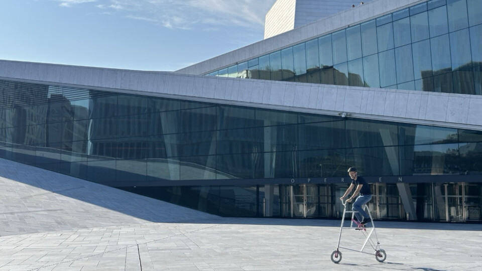 Man on a mini tallbike in front of the Oslo Opera house.
