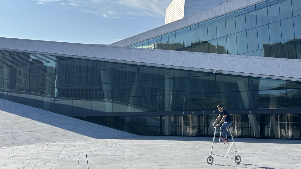Man on a mini tallbike in front of the Oslo Opera house.
