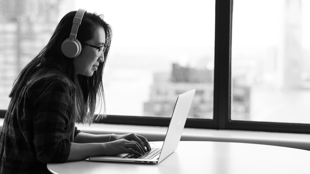 Woman works remotely with headphones on.