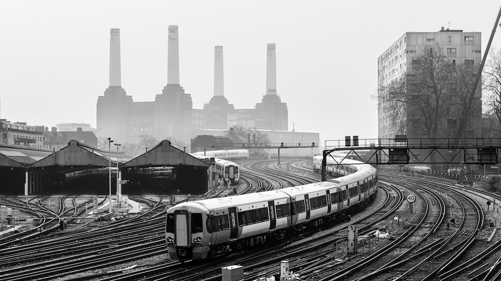 Battersea power station in the background. In the foregound a tube train and tracks. The picture is black and white.