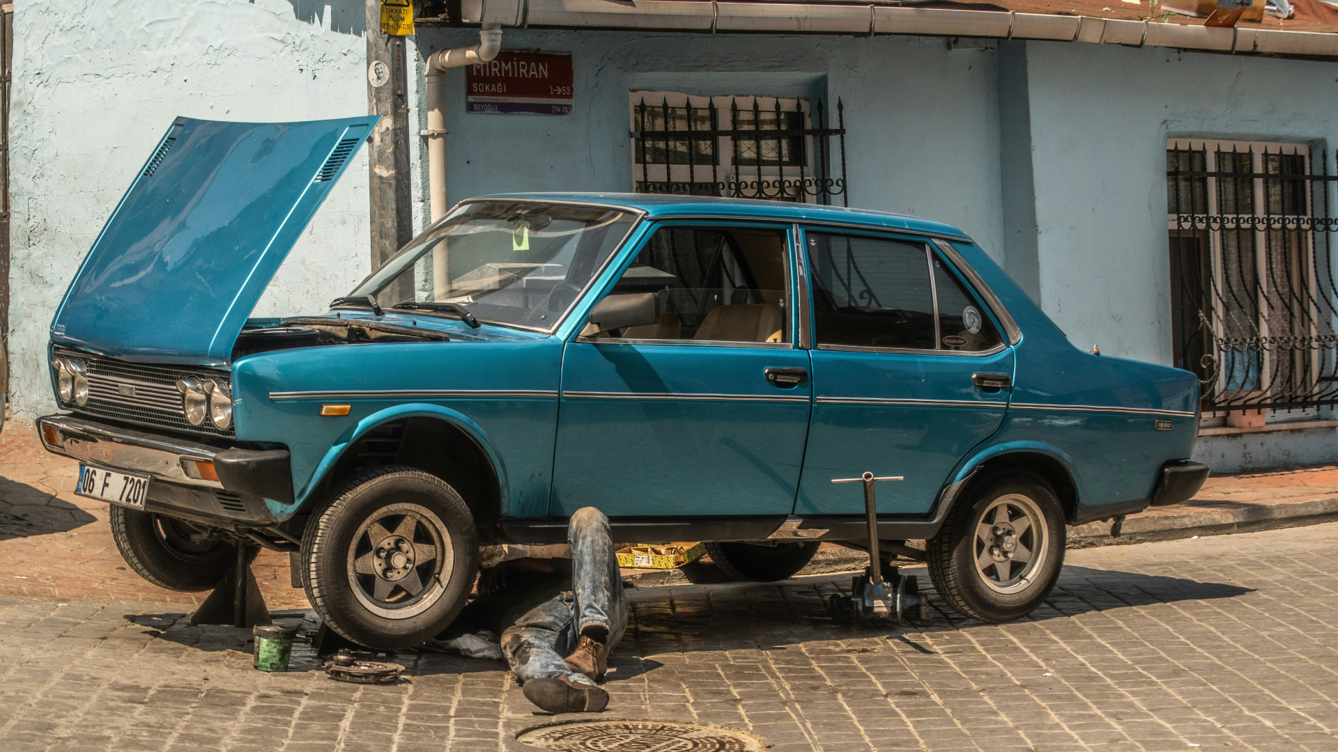 Man repairing his vintage car in the street.