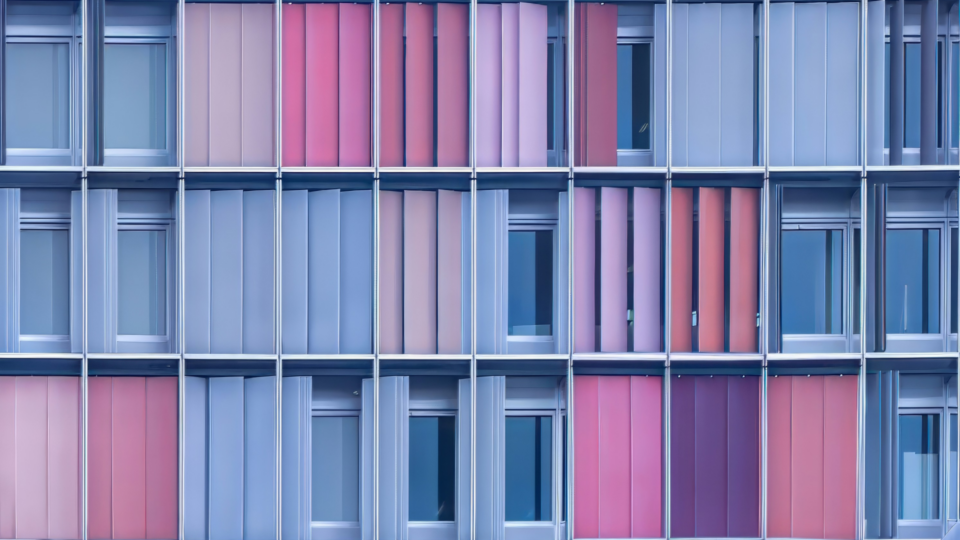 Windows of a large building with window covers either open, half shut or fully shut.