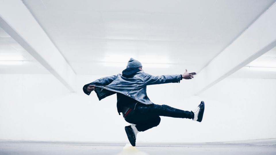Man dancing in a brightly lit parking garage.