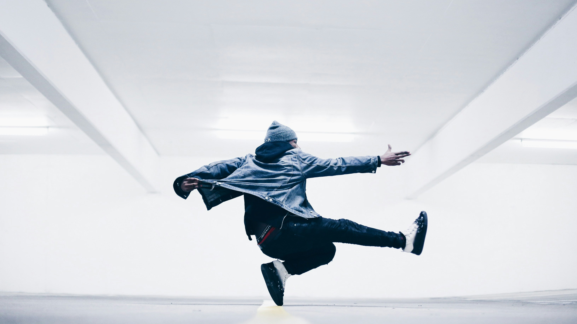 Man dancing in a brightly lit parking garage.
