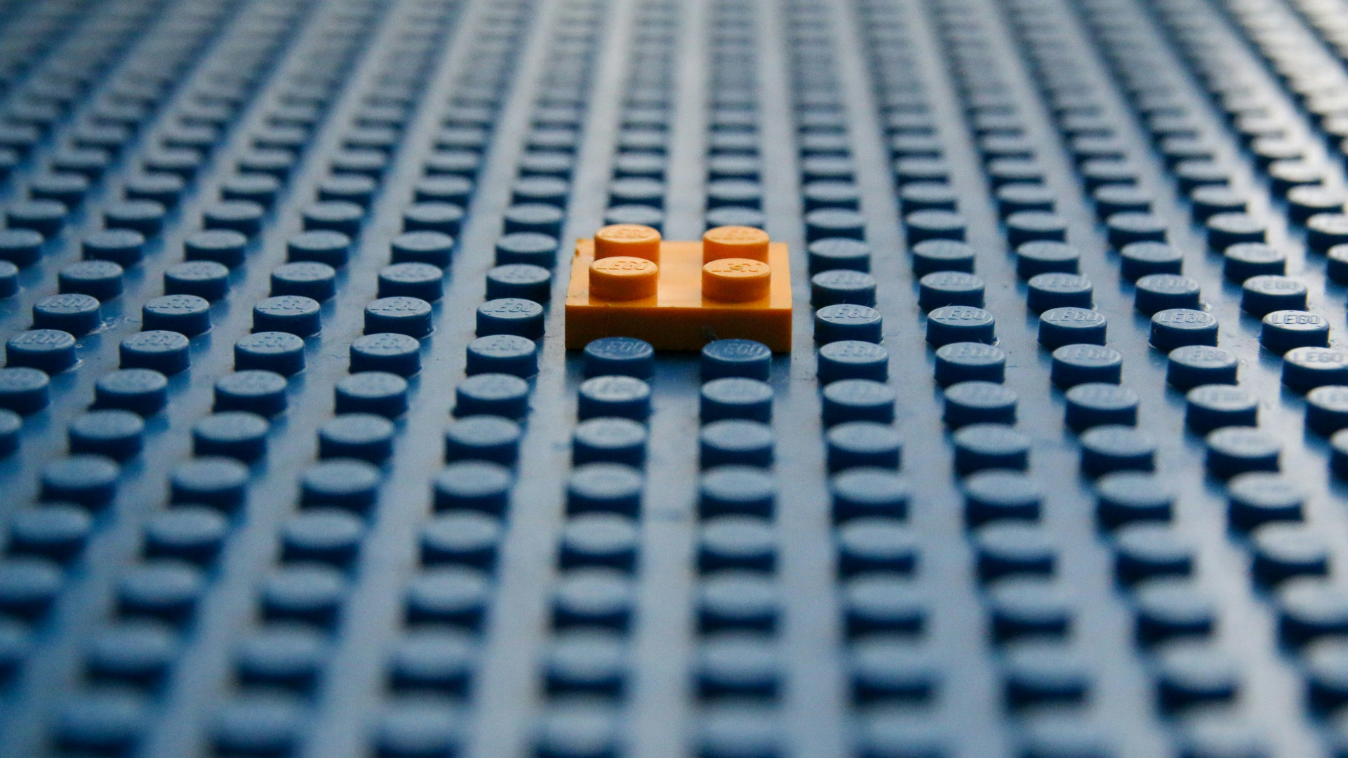 Thin orange four‑stud Lego brick placed on a blue baseplate