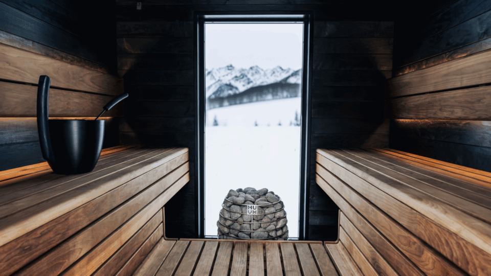 View of the inside of a sauna. A snowy landscape can be seen through the window.