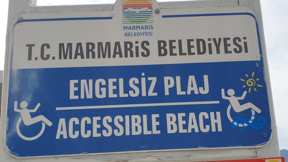 A sign from a beach that mentions accesiblity and has pictures of a wheelchair.