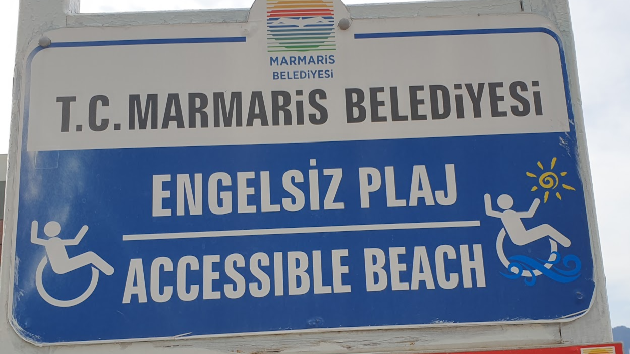 A sign from a beach that mentions accesiblity and has pictures of a wheelchair.
