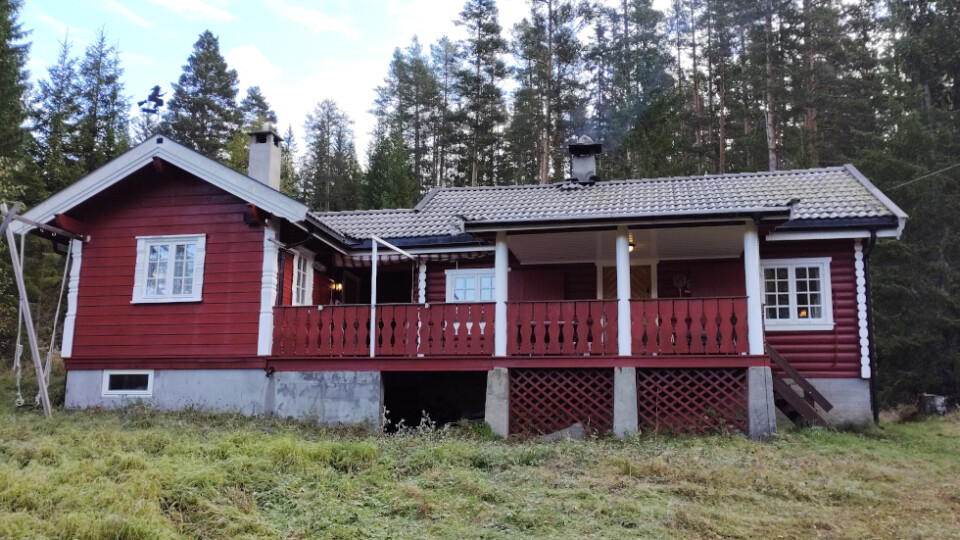 Red cabin in a wooded area.