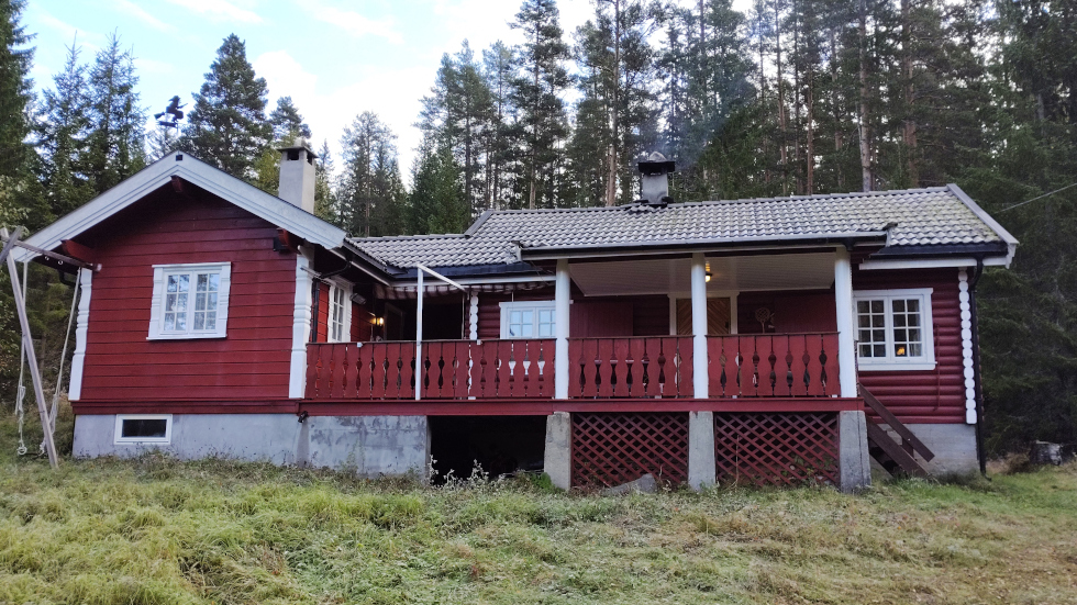Red cabin in a wooded area.