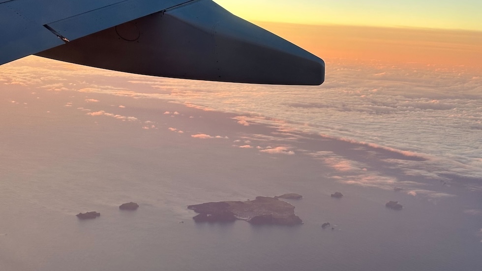 Vestmannaeyjar see from out of the window of a plane. The plane's wing is also visible.