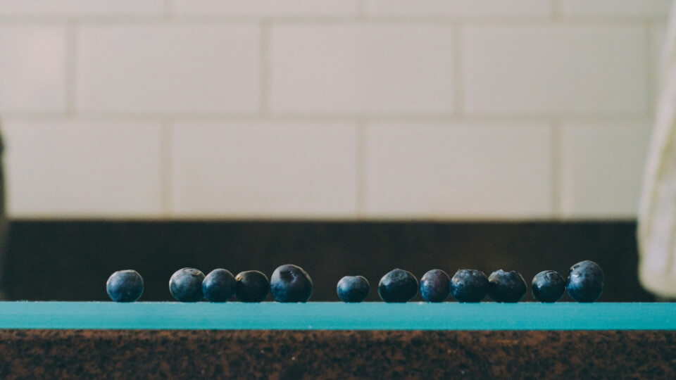 A side view of blueberries lined up in a row on a table.