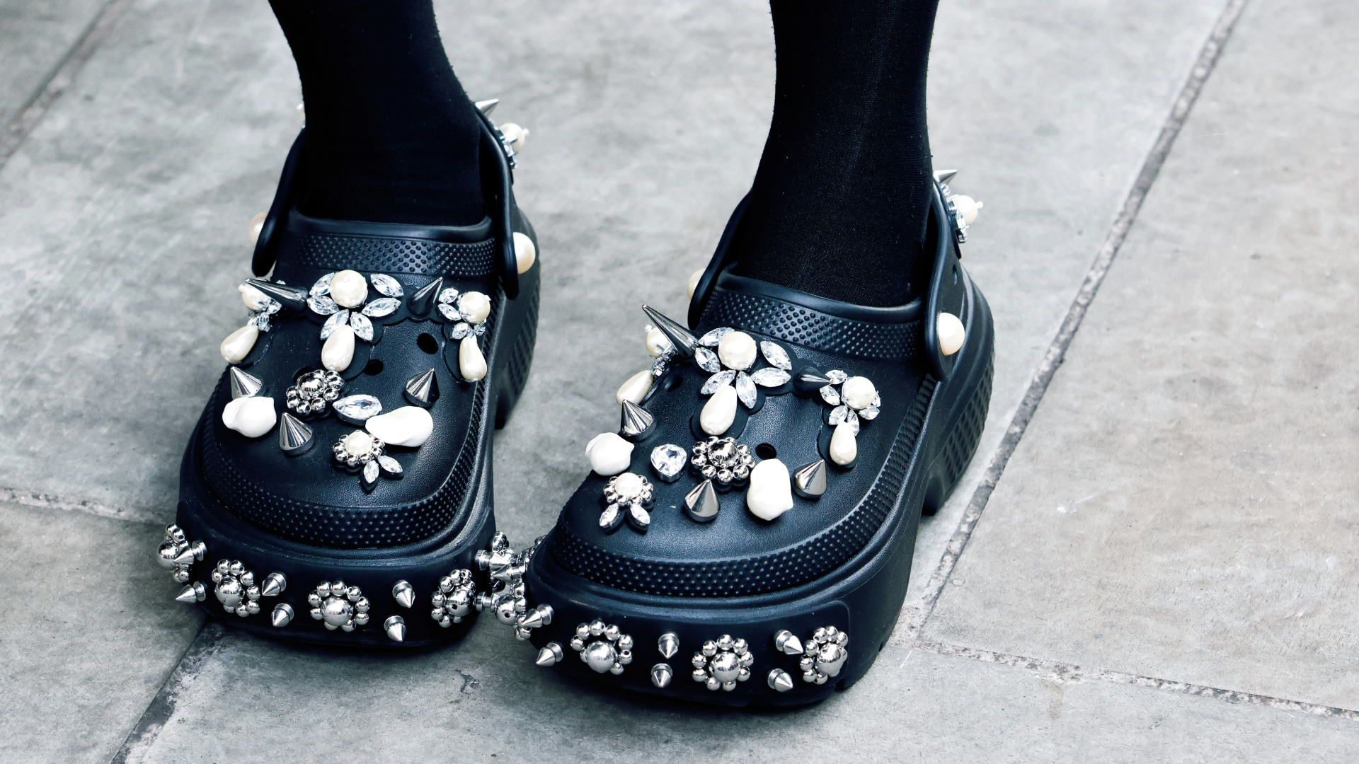 Black Crocs shoes with white and silver accessories.