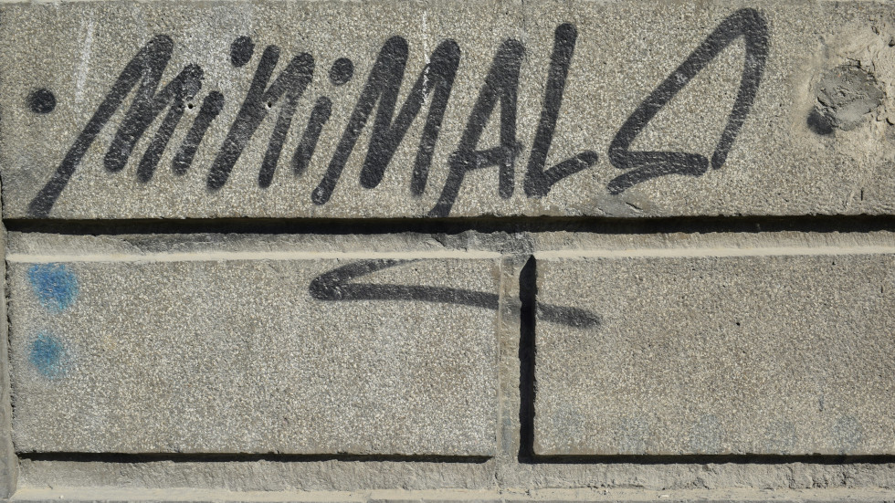 A wall with graffiti that says: minimal