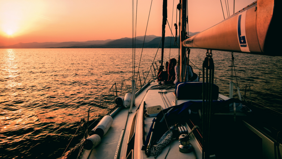 Sailboat on a sea during sunset with mountains in the background.