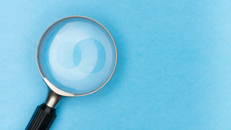 A magnifying glass resting on a blue background