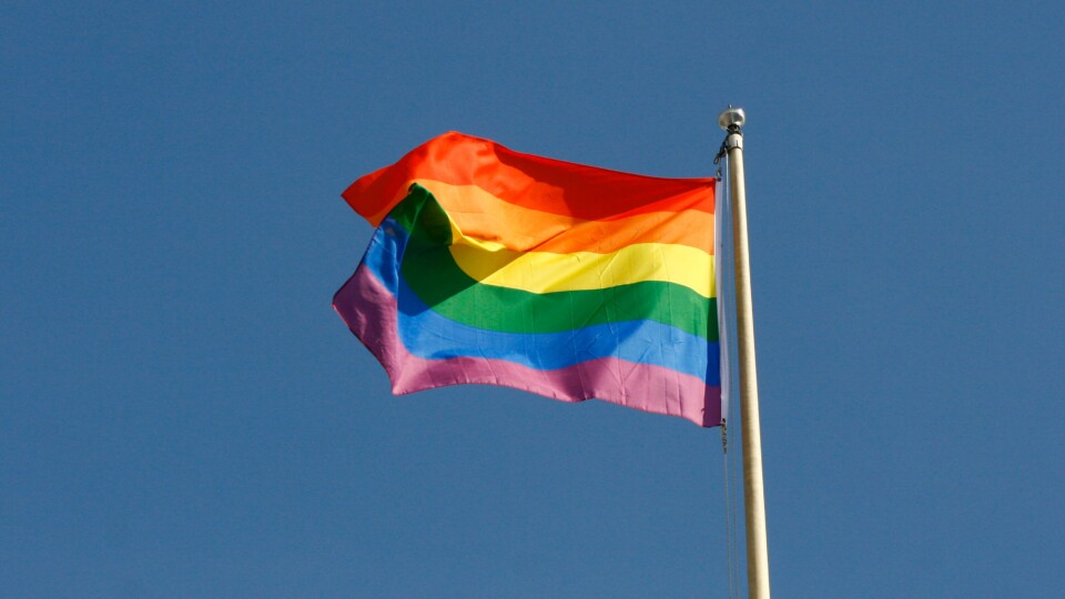 Pride flag waving in the wind with blue sky in the background