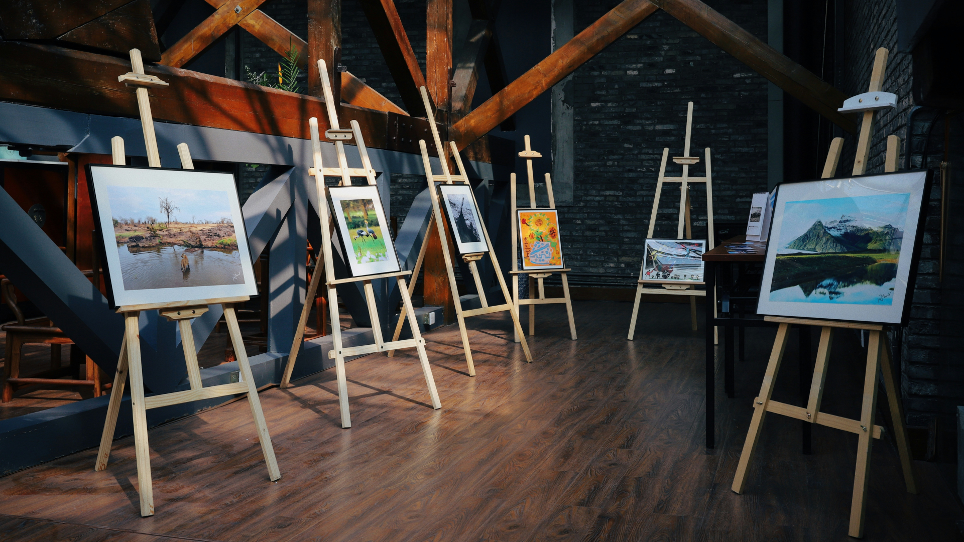 6 easels with paintings on them.