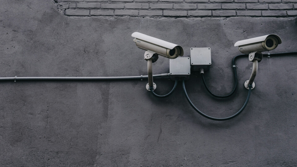 A black and white image of surveillance cameras mounted on a wall.