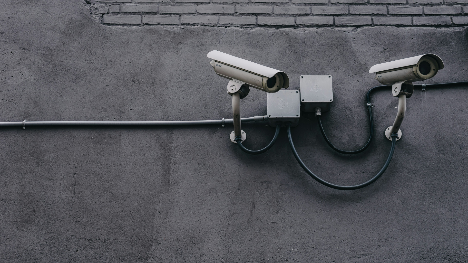 A black and white image of surveillance cameras mounted on a wall.