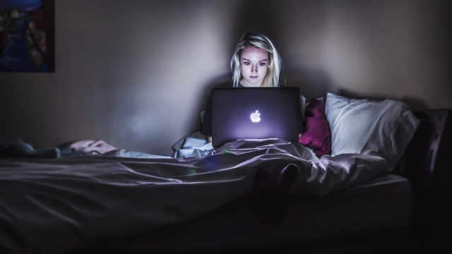 Woman in front of laptop in dark room - tracked by search engines.