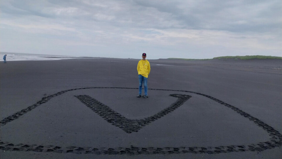 Man standing on black sand with a large Vivaldi logo crafted in that sand