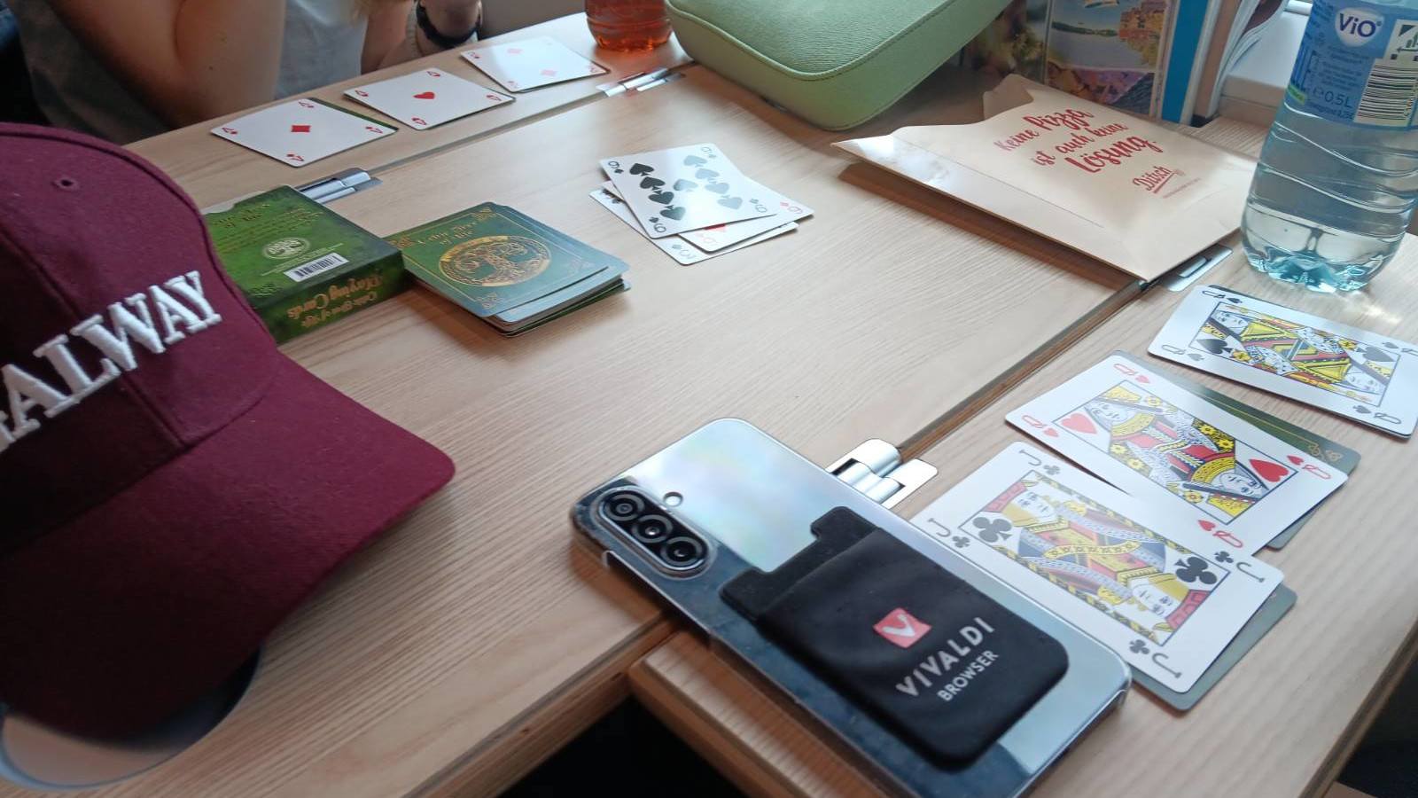 Assorted playing cards and travel items arranged on a train tabletop