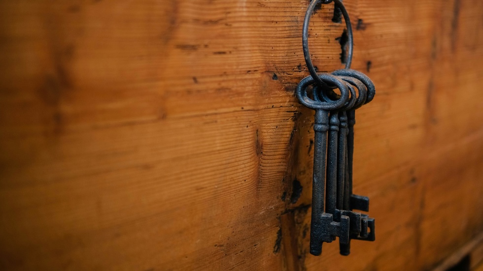 Viejas llaves negras en un gancho con un fondo de madera