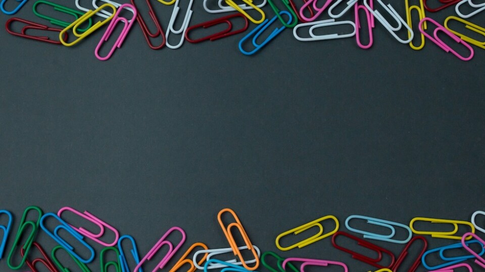Multicolored paperclips lying on a grey background