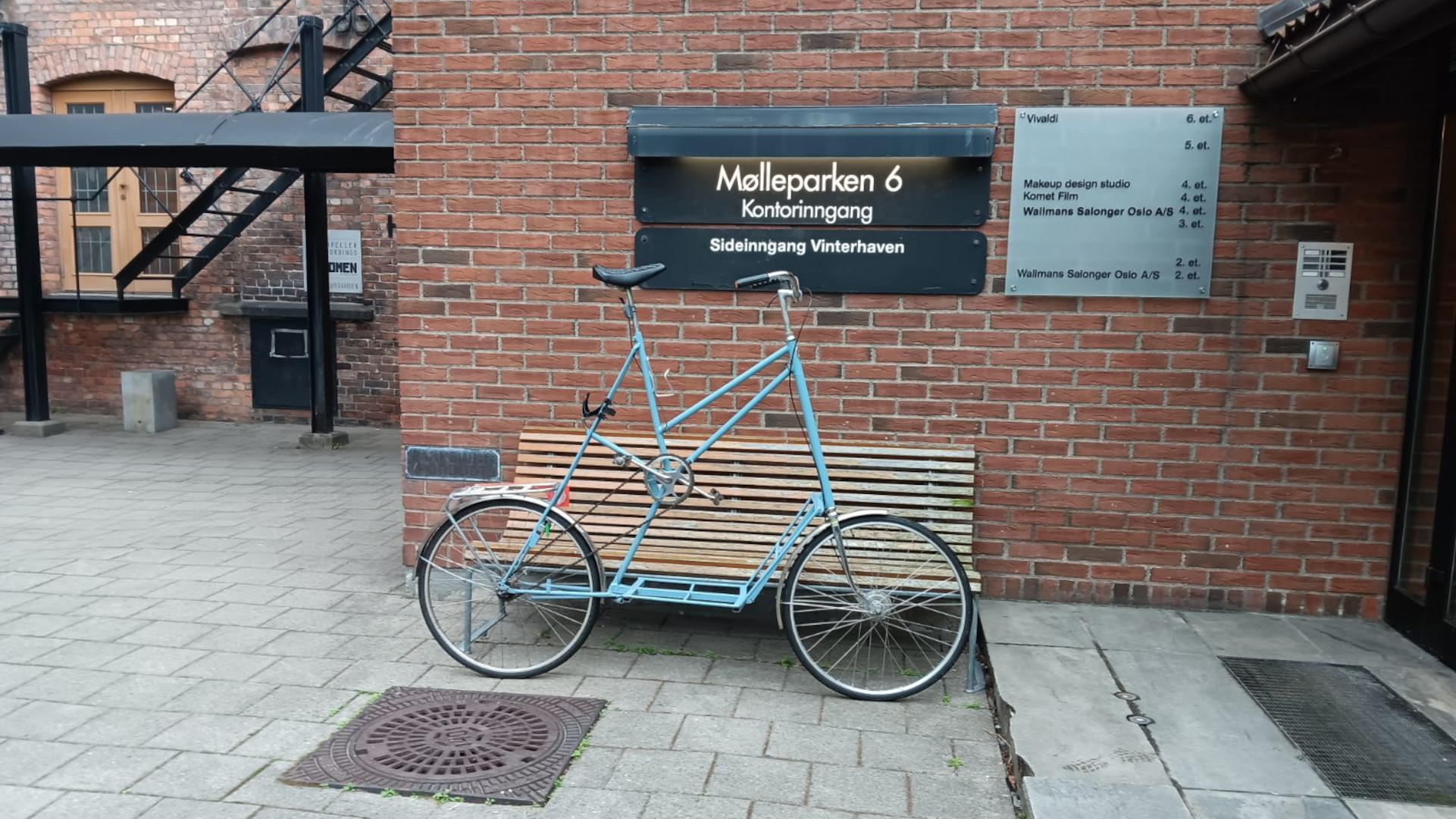 A blue tallbike in front of a sign that reads Møllerparken 6. There is a reference to Vivaldi on another sign to the right of that