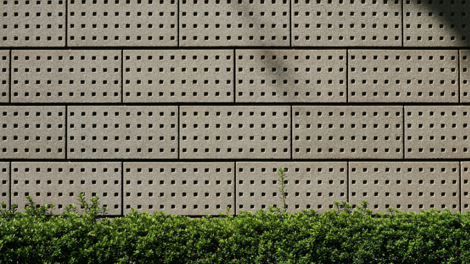 A wall of gray bricks, with a verge of grass along the bottom
